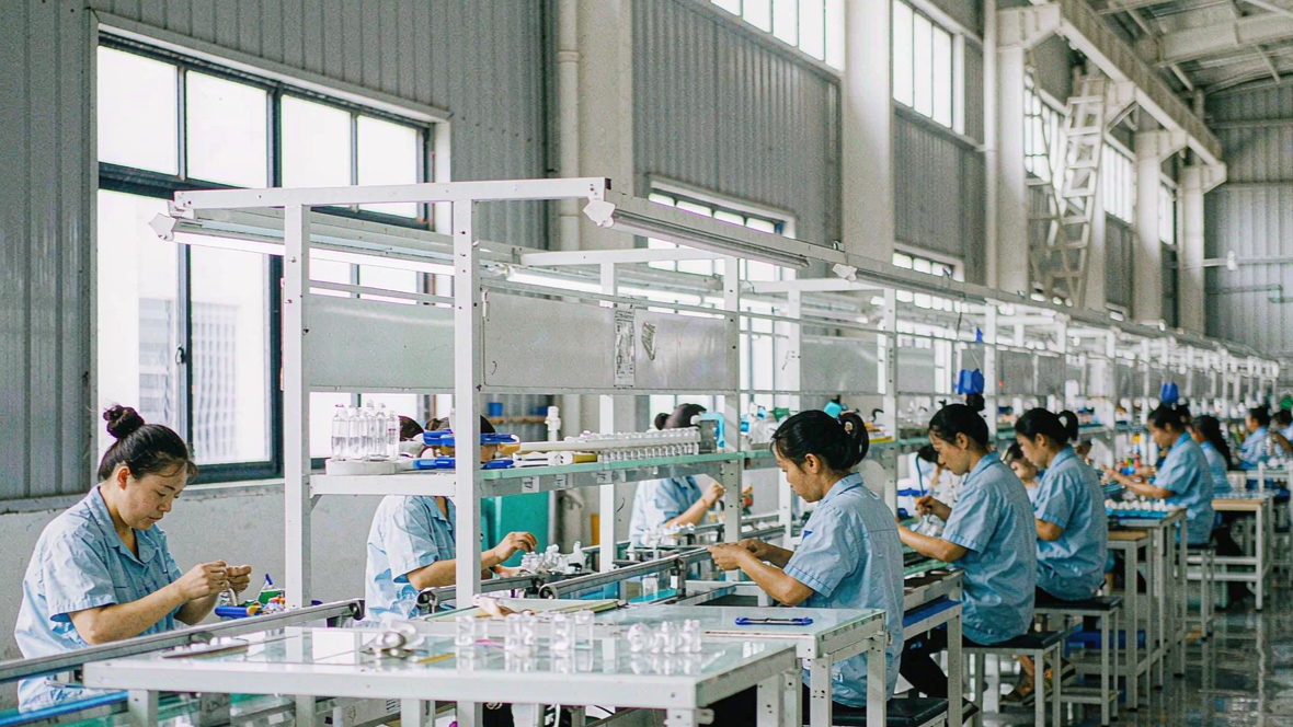 Workers assembling products along a conveyor line in a modern factory workshop