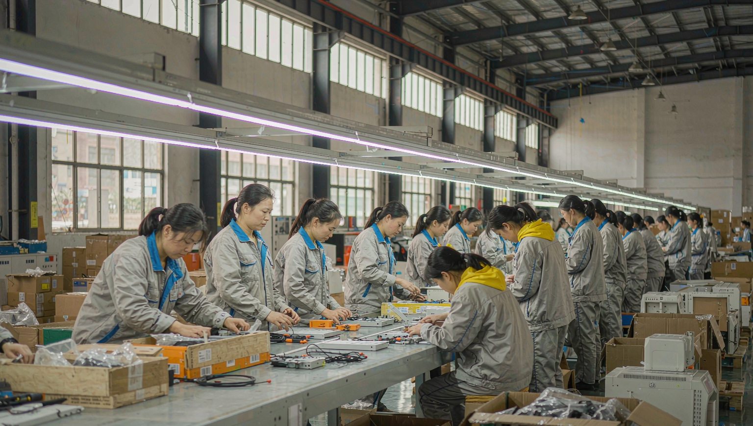 Workers assembling products along a conveyor line inside a light-manufacturing factory