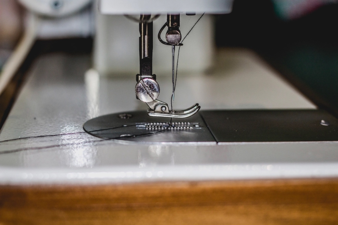 Close-up of an industrial sewing machine needle and presser foot stitching fabric