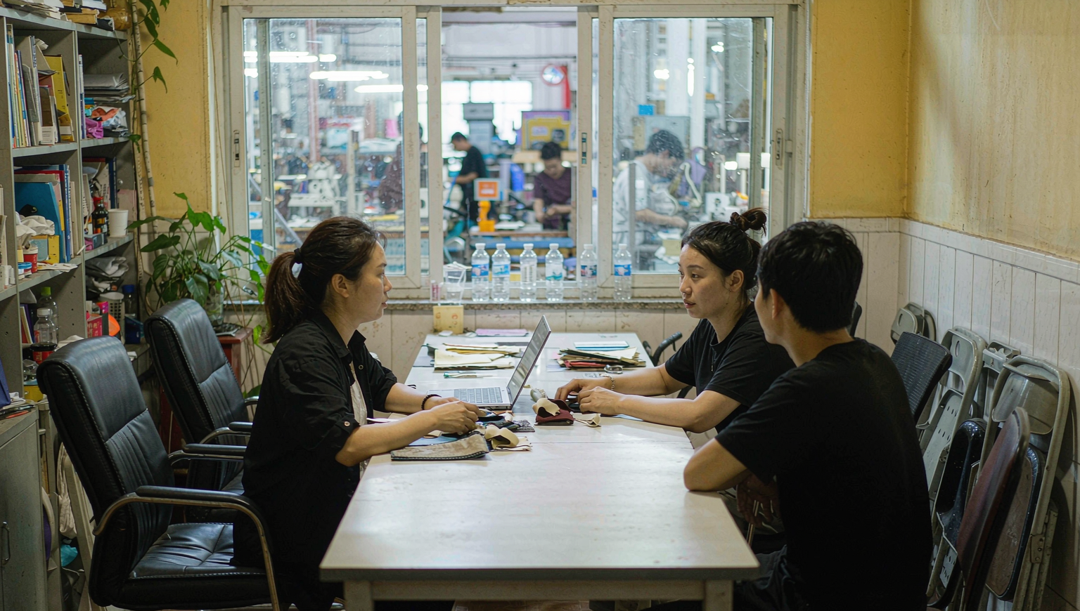 Buyers discussing product samples and specifications with a factory manager in a factory office