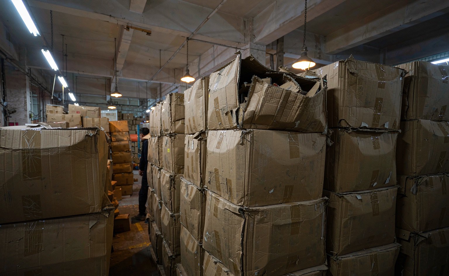 Stacks of export cartons of noticeably different quality in a warehouse